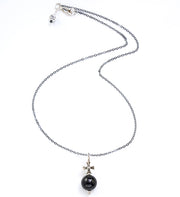 Modern Om ShungSilvCross necklace with black gemstone.